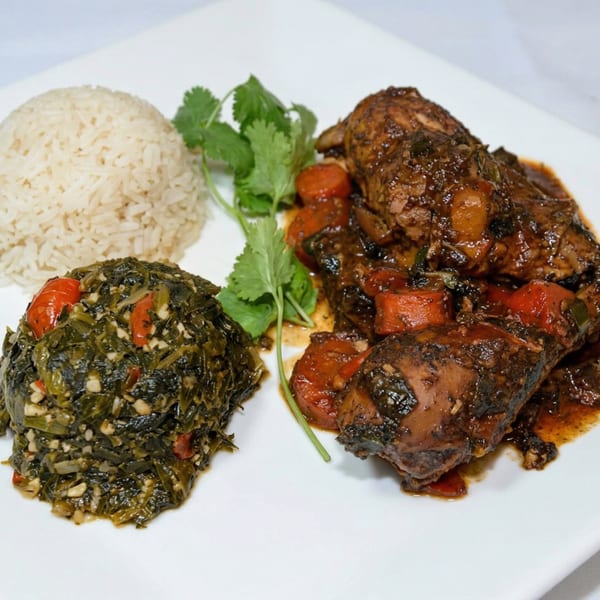 Savory chicken with carrots and sauce, served with rice and greens on a white plate.